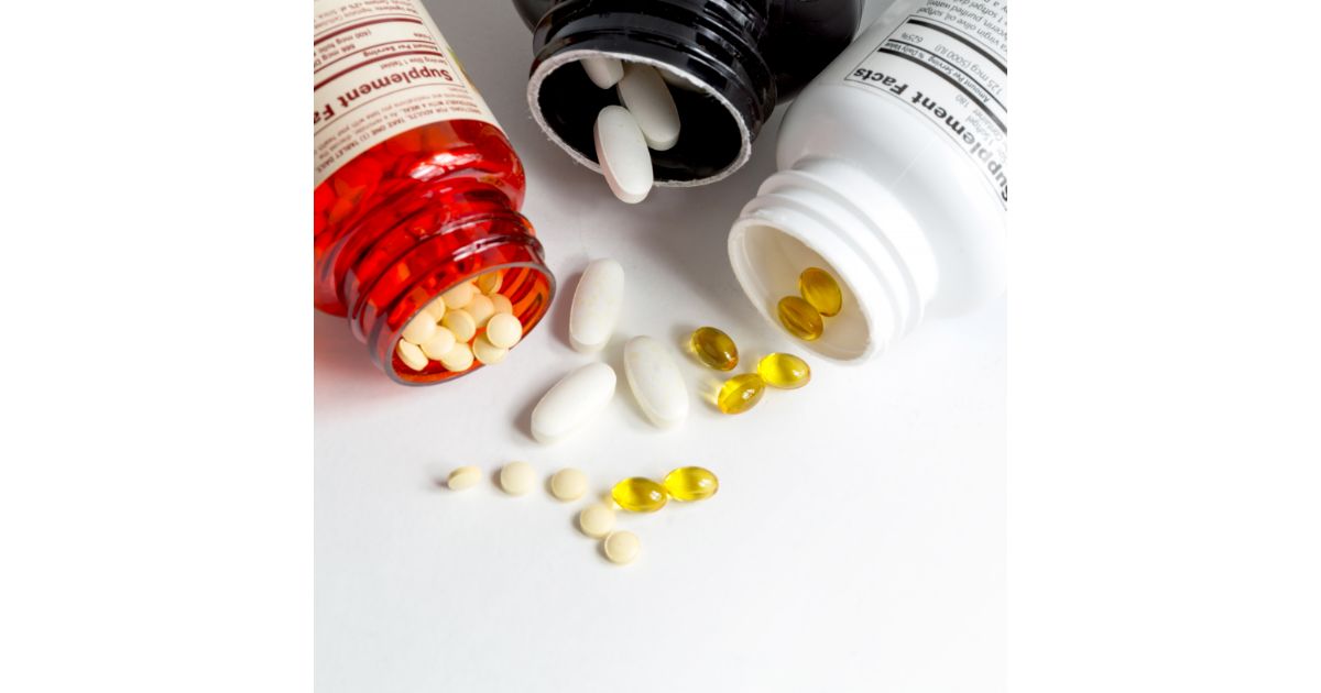 Assorted dietary supplement bottles with pills and capsules spilling out onto a surface.