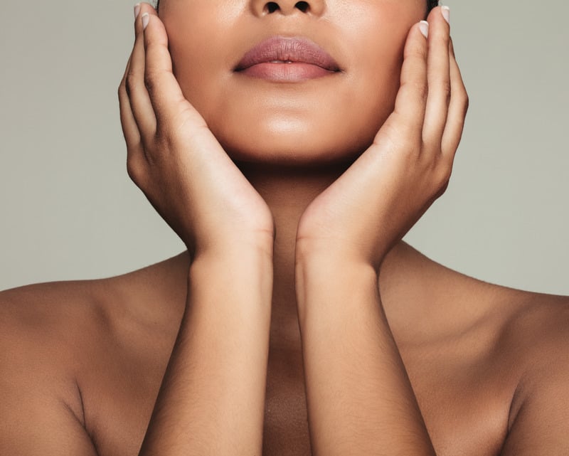 A close-up of a person gently holding their face with both hands, showcasing smooth, radiant skin. The image emphasizes skincare and rejuvenation.