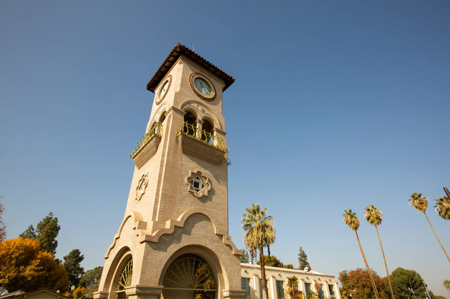 The historic Bakersfield Clock Tower under a clear blue sky with palm trees surrounding it, showcasing the city's iconic architecture.