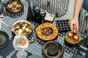 A gourmet meal served at a modern restaurant with dishes including a bowl of soup, salad, and appetizers, along with a glass of grapefruit drink on a stylish table.